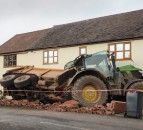 Tractor towing a trailer crashes through the front of a house